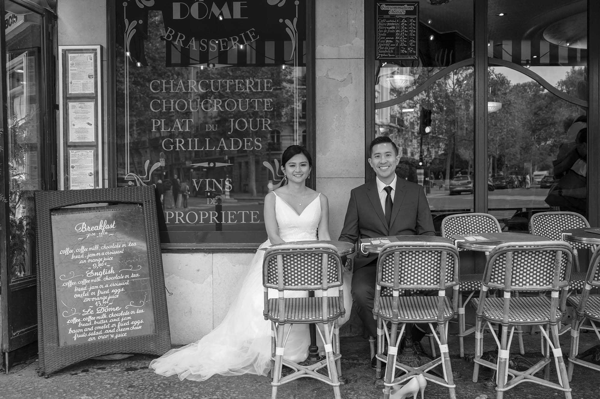 Newlyweds seated outside a classic Parisian café